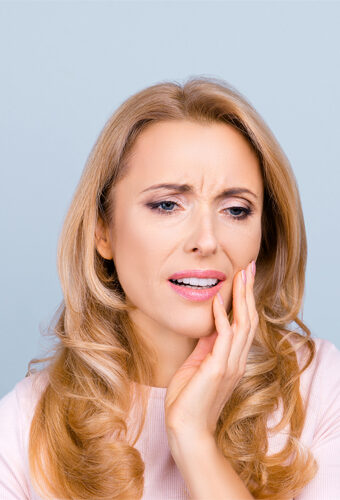 woman holding her jaw after gum graft surgery at Beach City Dental